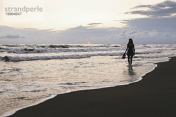 Frau spaziert an der Küste am Strand entlang