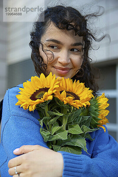 Happy woman holding bunch of sunflowers