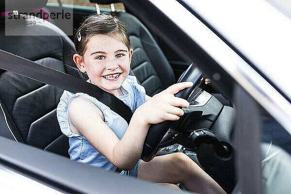 Glückliches Mädchen mit Lenkrad im Auto sitzend