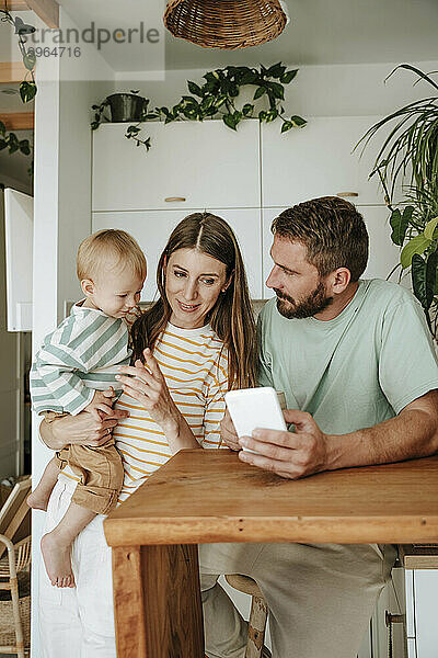 Familie mit kleinem Sohn schaut zu Hause aufs Handy