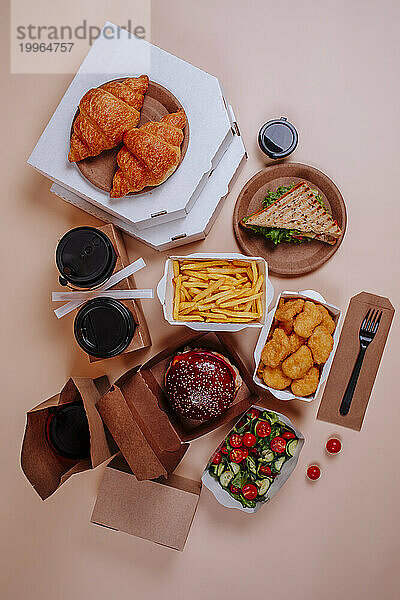 Varieties of fast foods with salad against beige background