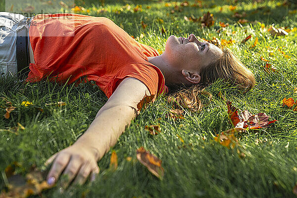 Nachdenkliche junge Frau entspannt sich im Gras im Park