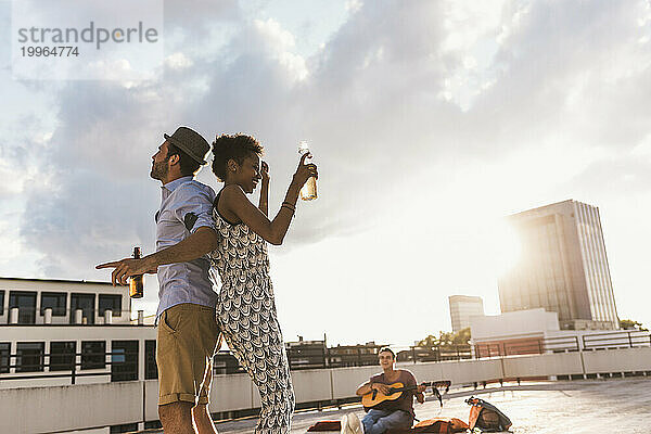 Mann und Frau halten Bier in der Hand und tanzen auf dem Dach