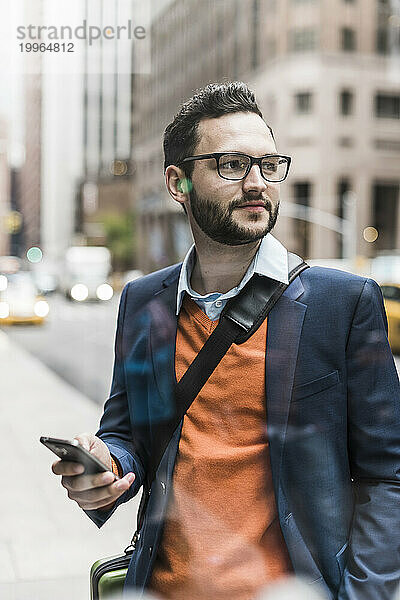 Geschäftsmann trägt eine Brille und hält ein Smartphone in der Hand