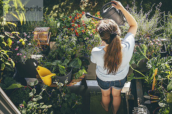 Frau gießt Pflanzen auf Balkon