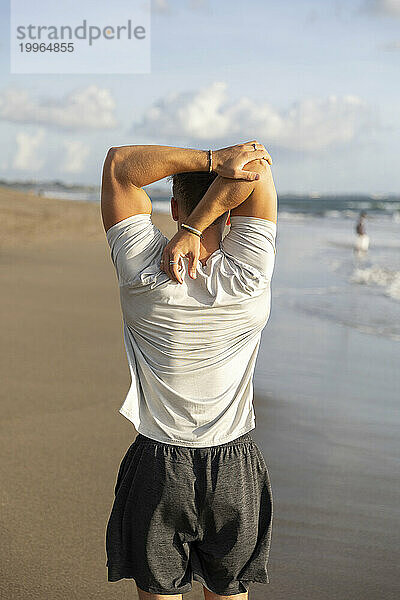 Man doing stretching exercise at beach