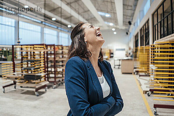 Geschäftsfrau mit verschränkten Armen lachend in der Industrie