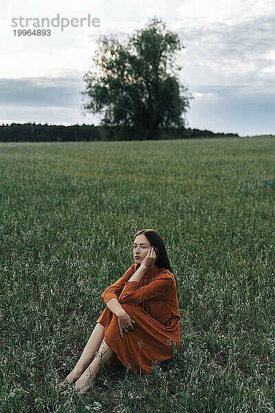 Nachdenkliche Frau sitzt im Maisfeld