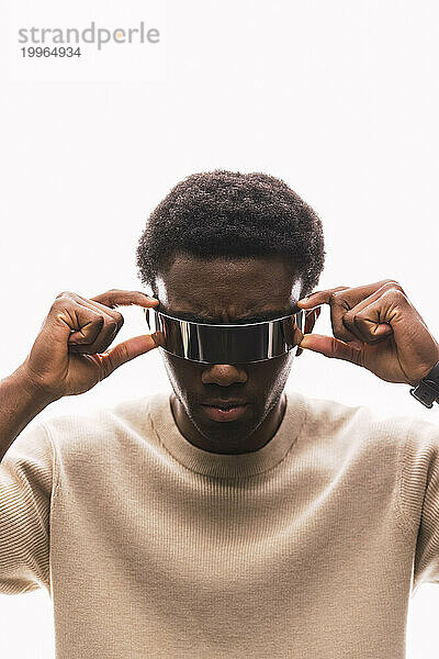 Cool young man adjusting cyber glasses against white background