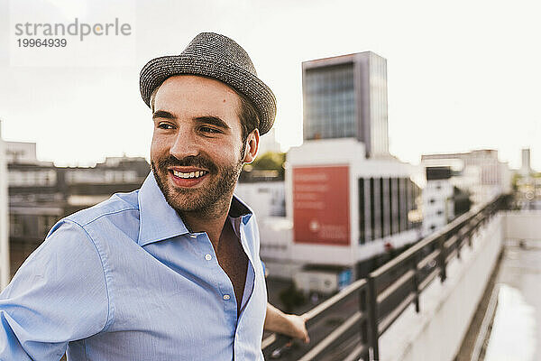 Smiling man wearing hat on rooftop