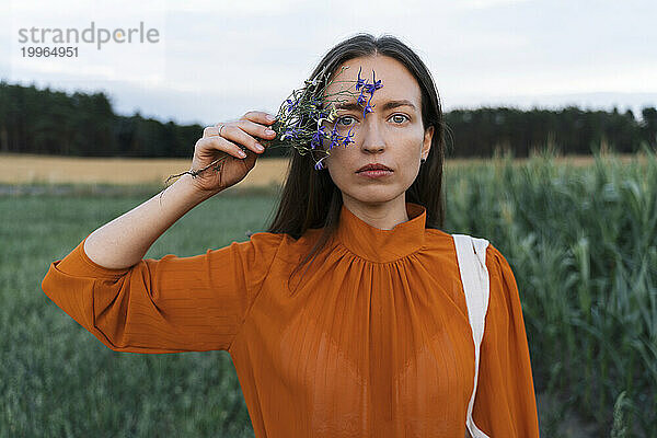 Frau hält blaue Blume im Feld