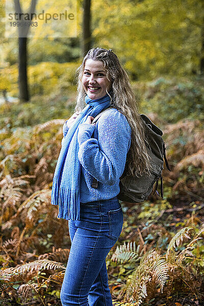Glückliche schöne Frau  die mit Rucksack im Cannock Chase Forest steht