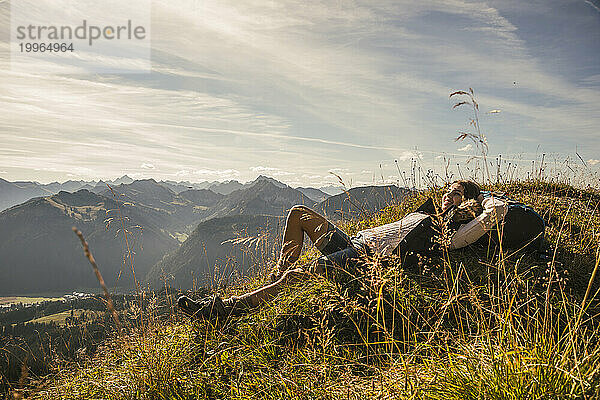 Young woman resting on rock in Tannheimer Tal  Tyrol  Austria