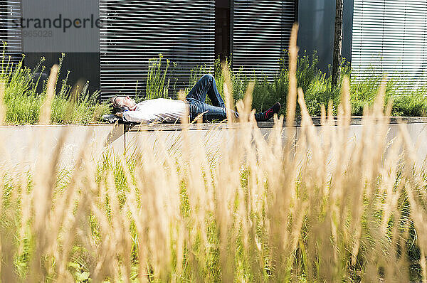 Geschäftsmann entspannt sich an einem sonnigen Tag in der Nähe eines Gebäudes