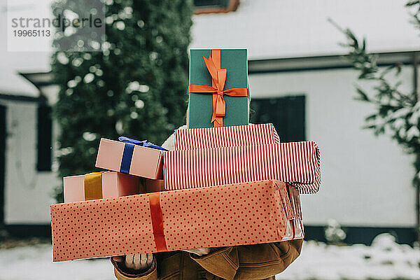 Frau bedeckt Gesicht im Winter mit Weihnachtsgeschenken