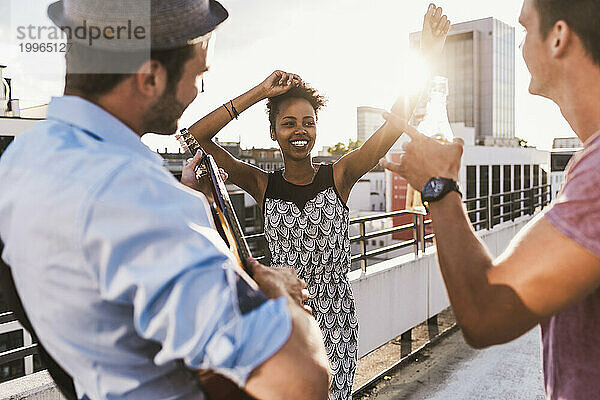 Lächelnde Frau tanzt mit Freunden auf dem Dach