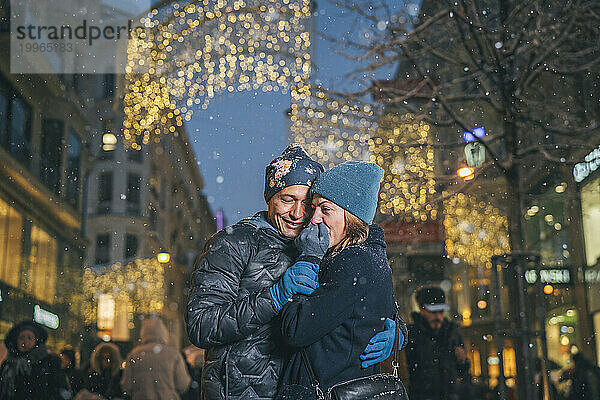 Glückliches Paar  das sich auf dem Weihnachtsmarkt umarmt und Spaß hat