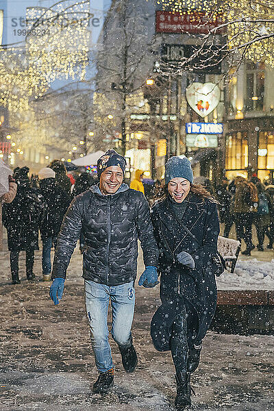 Glücklicher Mann und Frau laufen gemeinsam auf dem Weihnachtsmarkt