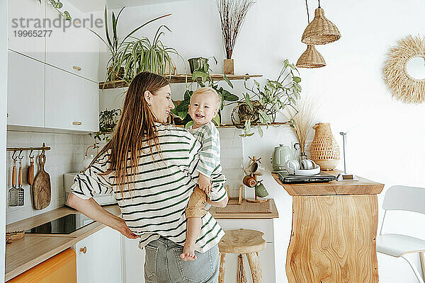 Mutter trägt Sohn in der heimischen Küche