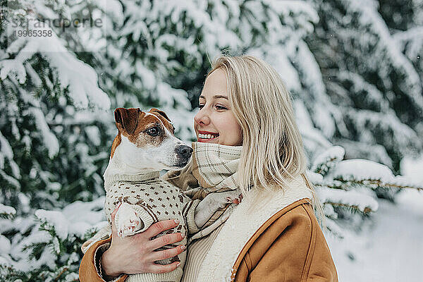 Glückliche Frau mit blonden Haaren  die einen Hund im Arm hält