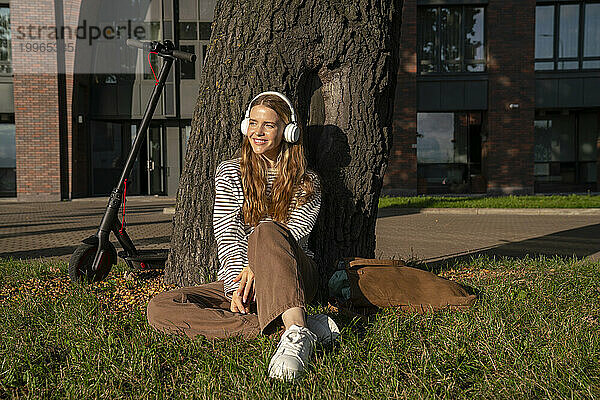 Frau hört im Park Musik über kabellose Kopfhörer