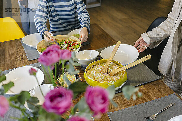 Mädchen serviert Essen mit Großmutter am Esstisch zu Hause