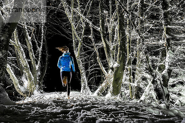 Frau läuft nachts im Winterwald