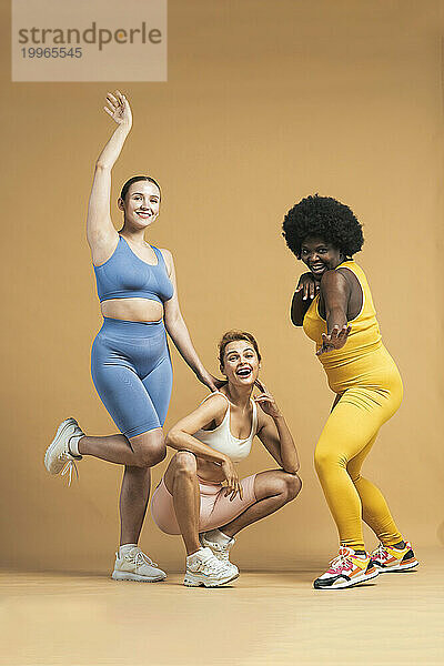 Cheerful multiracial women against beige background