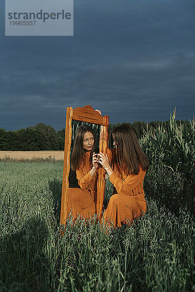 Frau mit Spiegelbild im Spiegel am Maisfeld