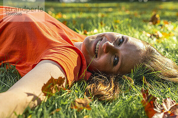 Glückliche junge Frau entspannt sich im Gras im Park
