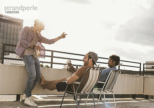 Carefree friends enjoying on rooftop under sky