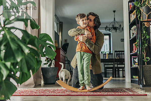 Loving father kissing son standing on board at home