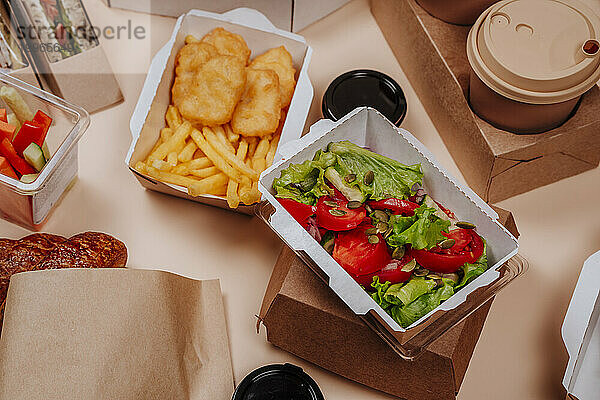 Tomato and lettuce salad with fast foods against beige background