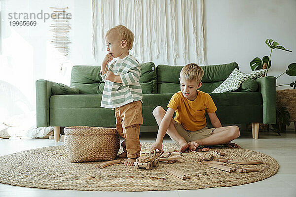 Two brothers playing with wooden train set in living room at home