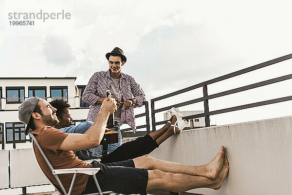 Freunde feiern mit Bier auf dem Dach unter freiem Himmel