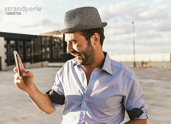 Glücklicher Mann fotografiert mit Smartphone auf der Terrasse