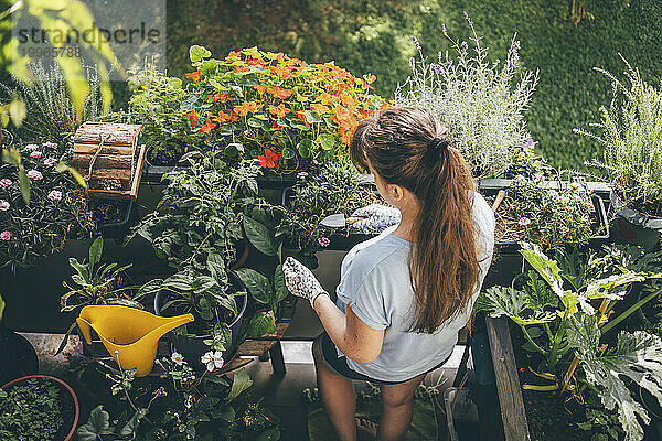 Frau hält Kelle in der Hand und erledigt Gartenarbeit auf dem Balkon