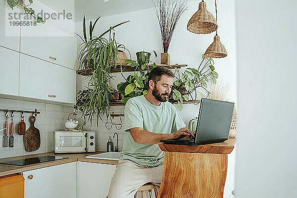 Mann benutzt Laptop in der heimischen Küche