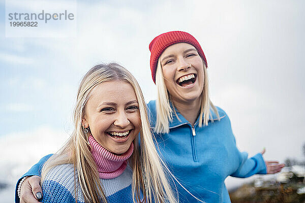 Lächelnde Freunde  die im Winter unter dem Himmel genießen
