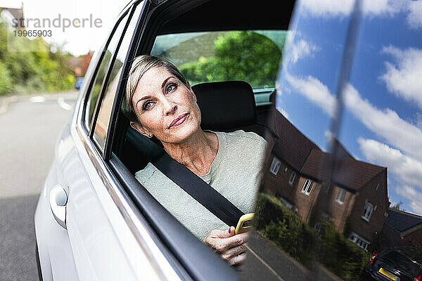 Reife Frau lehnt am Fenster und sitzt im Auto