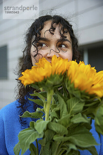 Junge Frau mit lockigem Haar  das nach Sonnenblumen riecht