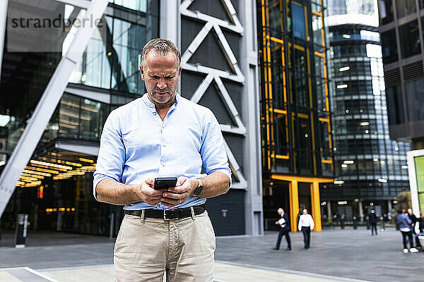 Reifer Geschäftsmann nutzt Smartphone im Büropark