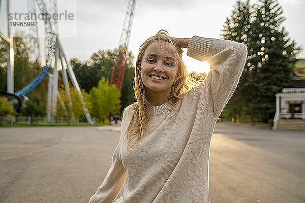Glückliche junge Frau im Vergnügungspark bei Sonnenuntergang