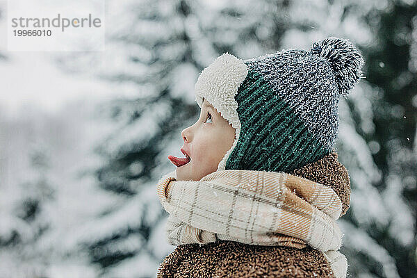 Netter Junge fängt im Winter Schnee mit der Zunge