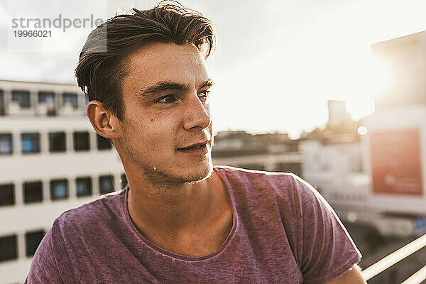 Thoughtful young man on rooftop at sunset