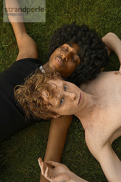 Young gay couple lying together on grass