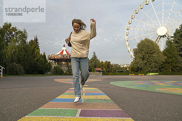 Cheerful woman enjoying and jumping in amusement park