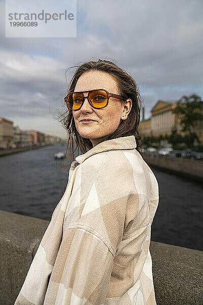 Lächelnde Frau mit Sonnenbrille und stehend am Fluss