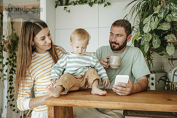 Familie mit kleinem Sohn schaut zu Hause aufs Handy