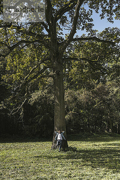 Älterer Mann steht vor Baum im Park